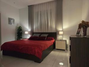 a bedroom with a bed with a red bedspread at Eivissa Apartment in Marsaskala