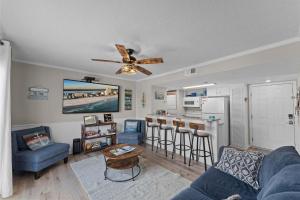 a living room with a blue couch and a ceiling fan at Beachfront - 2 Bedrooms - Big Screen TV in Gulf Shores +28 photos