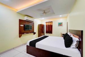 a bedroom with a bed and a tv on the wall at Hotel Mini Escape Perungalathur in Chennai