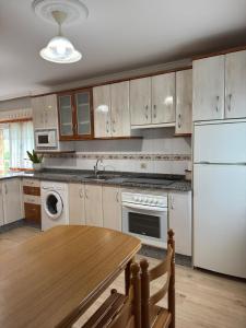 a kitchen with a table and a white refrigerator at Apartamentos Casa Alvarina - Luarca in Cortina