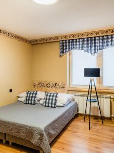 a bedroom with a bed and a lamp and a window at WERONIKA Murzasichle - podgrzewany basen zewnętrzny śniadanie i jacuzzi w cenie in Murzasichle