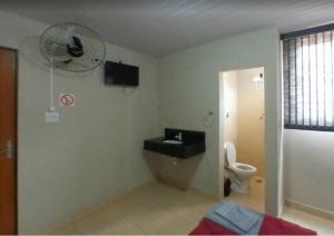 a bathroom with a toilet and a fan on the wall at Cedro Assis hotel in Assis