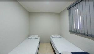 two beds in a small room with a window at Cedro Assis hotel in Assis