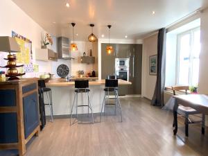 a kitchen with a counter and bar stools in it at Charisma - 2 chambres Proche hypercentre in Pontarlier