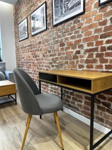 a desk and a chair in front of a brick wall at SILESIAN LOFT Apartment in Ruda Śląska +18 photos