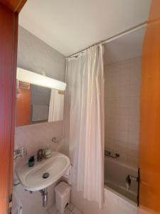 a bathroom with a sink and a shower curtain at Alpstay - Résidences des Bains d'Ovronnaz - Studio SUD S204 in Ovronnaz +3 photos