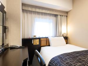 a hotel room with a bed and a desk and a window at APA Hotel Kanazawa Ekimae in Kanazawa