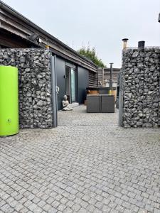 a building with a stone wall and a green object at Relax Trois Bornes - De Grenspost in Gemmenich