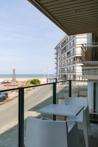 a table and chairs on a balcony with a view of the beach at Blankeduyn Koksijde in Koksijde