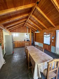a large kitchen with a table and a refrigerator at Cabañas EL CAMPITO in Aluminé