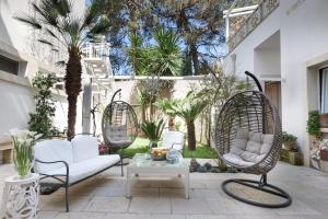 d'une terrasse avec 2 chaises, une table et des palmiers. dans l'établissement Palazzo Dei Dondoli, à Lecce