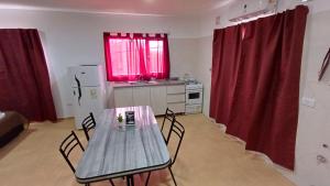 a table and chairs in a kitchen with red curtains at Complejo CRISMAR in Las Grutas