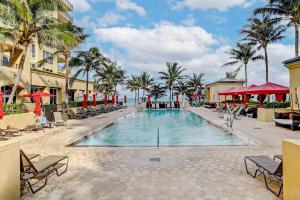 a swimming pool with chairs and palm trees in a resort at 2B Beachfront condo! Pool! Games! 15 mins to PBI! in Riviera Beach
