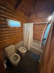 a bathroom with a toilet and a bathtub at Cabañas EL CAMPITO in Aluminé