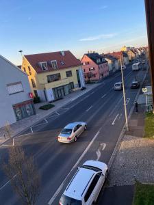 a street with cars driving down a street with buildings at Cozy room with bathroom in a private house in Bergrheinfeld