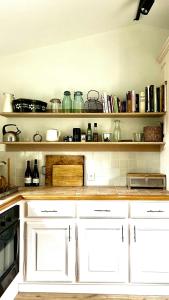 a kitchen with white cabinets and a shelf with jars at Charming House In Lyons-La-Forêt in Lyons-la-Forêt