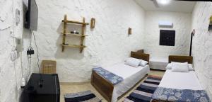a room with two beds and a tv in it at لودج ادرار احكيك in Siwa