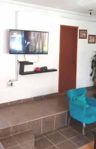a living room with a blue chair and a tv at Hermosa Casa Colibri in Oaxtepec