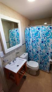 a bathroom with a toilet and a sink and a shower curtain at Complejo CRISMAR in Las Grutas +19 photos