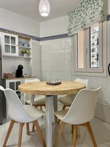 a kitchen with a wooden table and white chairs at El Orbayín de Llastres in Lastres +30 photos