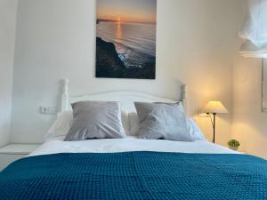 a white bed with a blue blanket and pillows at El Orbayín de Llastres in Lastres