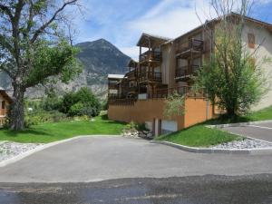 a building with a parking lot in front of a mountain at Les Allobroges C03 in Guillestre