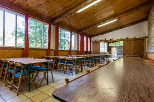 una fila de mesas y sillas en una habitación con ventanas en Alberg La Solana, en Salàs de Pallars