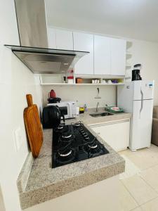 a kitchen with a stove and a white refrigerator at Praia dos Corais apt 79 in Santa Cruz Cabrália +5 photos