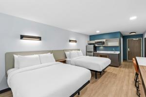 a hotel room with two beds and a kitchen at StudioRes by Marriott Jacksonville Orange Park in Orange Park