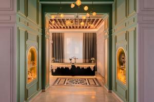 a hallway with green walls and a chandelier at Eugenia de Montijo, Autograph Collection in Toledo