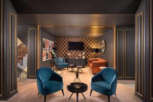 a living room with blue chairs and a piano at Eugenia de Montijo, Autograph Collection in Toledo