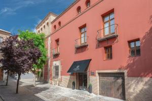 a red building with a tree in front of it at Eugenia de Montijo, Autograph Collection in Toledo