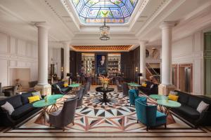 a lobby with couches and tables and a stained glass ceiling at Eugenia de Montijo, Autograph Collection in Toledo