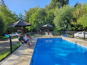 a man and woman sitting in chairs next to a swimming pool at Las Victorias in Salto del Laja
