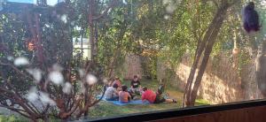 a group of people sitting on a blanket in the grass at Hostal Arboretum cafeteria & jardin in Hijuelas