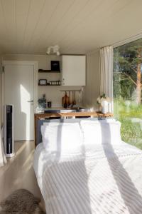 a bedroom with a bed with white sheets and a window at Gnist Retreat in Sørumsand