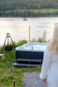 a woman walking past a tub next to a body of water at Gnist Retreat in Sørumsand +19 photos