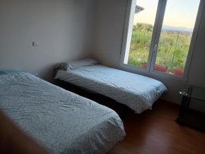 two beds in a small room with a window at Chalet en Sieteiglesias, Sierra Norte de Madrid in Sieteiglesias