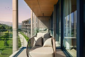 a chair on a balcony with a view of a building at Paragraph Golf & Spa Tabori, Autograph Collection in Tbilisi City