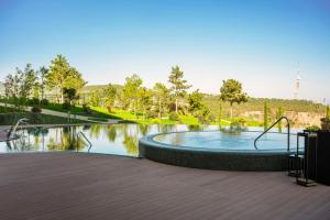 a swimming pool in a park with trees and water at Paragraph Golf & Spa Tabori, Autograph Collection in Tbilisi City