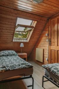 a attic bedroom with two beds and a window at Domek "Kasieńka" in Stronie Śląskie