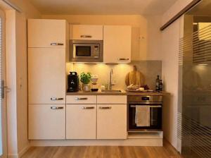 a kitchen with white cabinets and a microwave at Wohlfühlapartment GUXHAGEN- nähe Bahnhof & A7, schnell in Kassel in Guxhagen