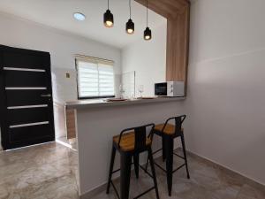 a kitchen with two black stools at a counter at Apart Continente Park in San Clemente del Tuyú