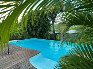a blue swimming pool with a wooden deck and palm trees at Maryvent Apartment in Sainte-Anne