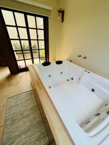 a large white bath tub in a room with a window at Studio com Jacuzzi na Natureza Casal Baoba Suite in Bombinhas +11 photos