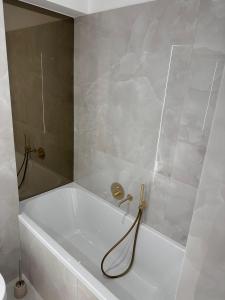 a white bath tub with a hose in a bathroom at Cortina - Yard & Wellness View in Voluntari +8 photos
