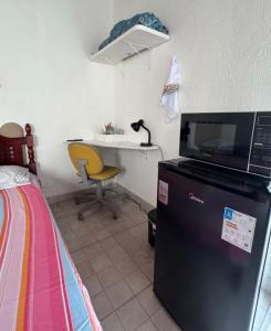 a room with a bed and a desk with a microwave at SuÍte 4 com Ar Condicionado, Wi-Fi e Netflix in Jundiaí
