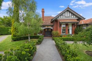 a red brick house with a tree and bushes at Complete Host Brighton House in Melbourne