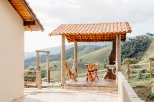 a wooden deck with a gazebo and a chair at Chalé Romântico em Itamonte-MG in Itamonte