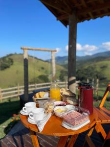 a table with food on top of a wooden table at Chalé Romântico em Itamonte-MG in Itamonte